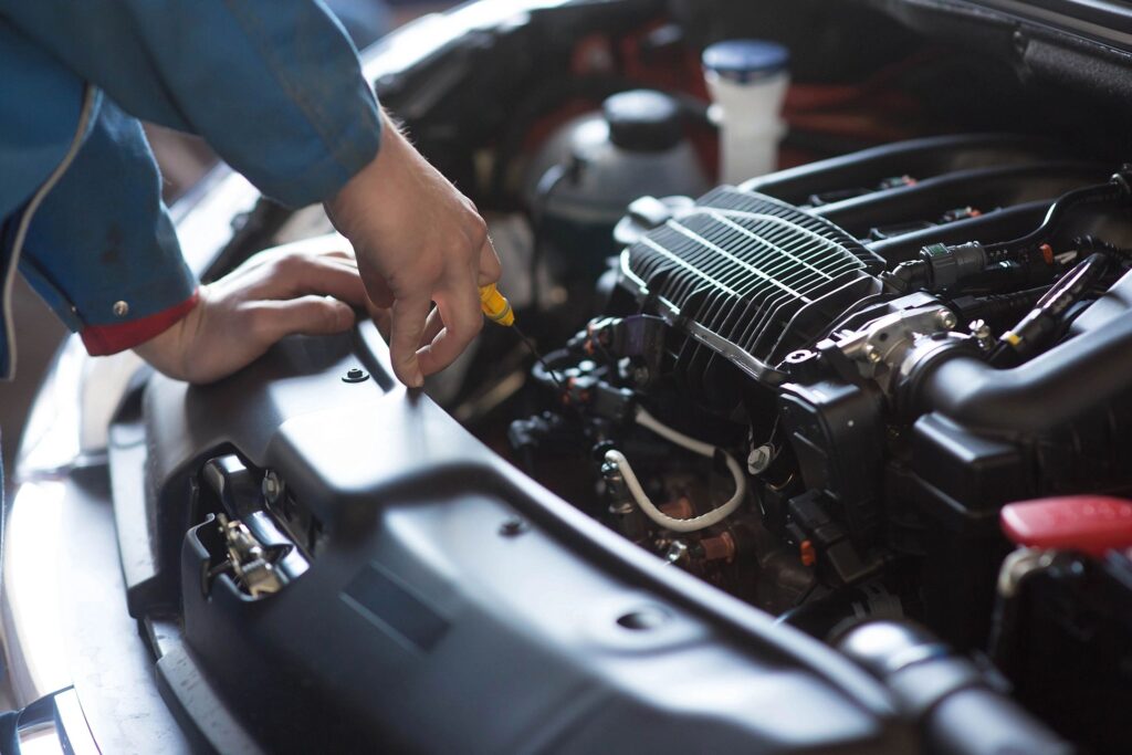 “Auto technician inspecting a car engine during routine maintenance.”